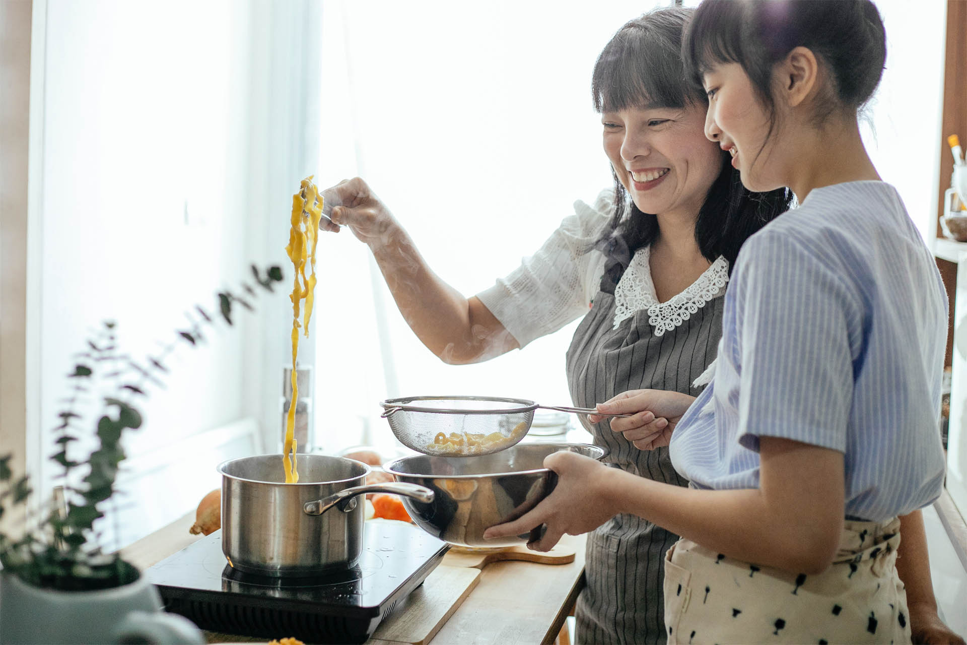 Couple cooking pasta happily in the kitchen together.